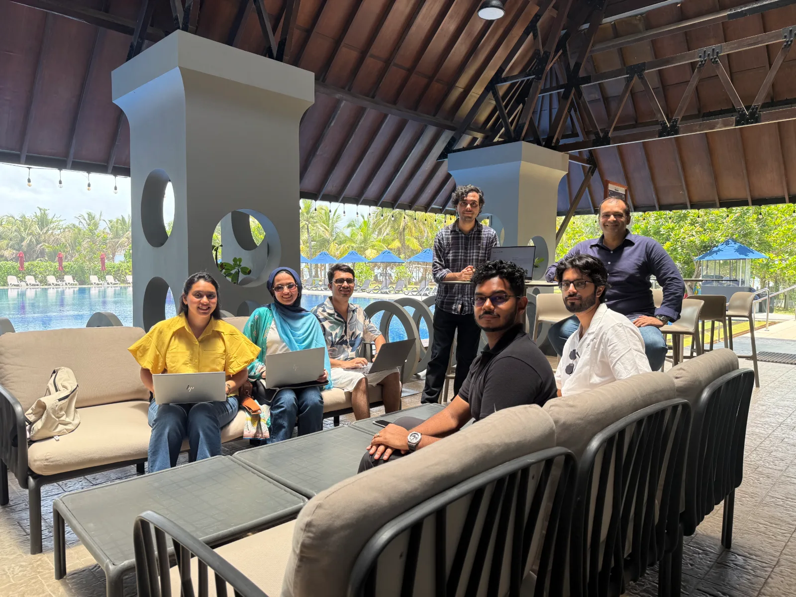 The team working on laptops in a poolside lounge